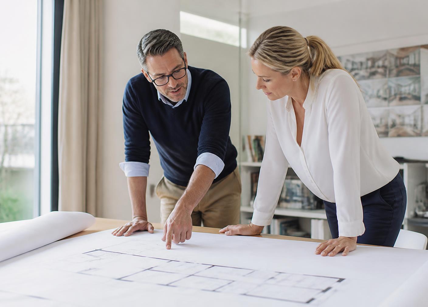 Twee adviseurs bespreken een plattegrond aan tafel